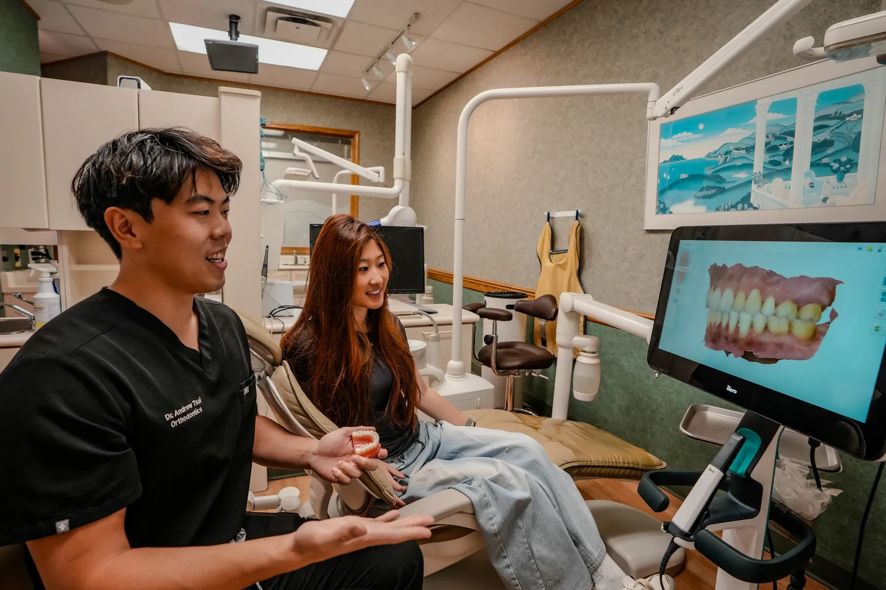 Dr. Andrew Tsai talking with a patient in the chair, reviewing a scan